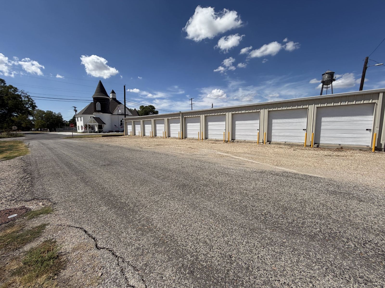Street view of storage buildings with neighboring church and water tower